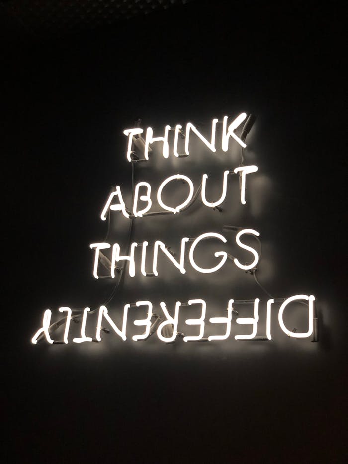 A glowing neon sign displaying an upside-down motivational quote against a dark background.