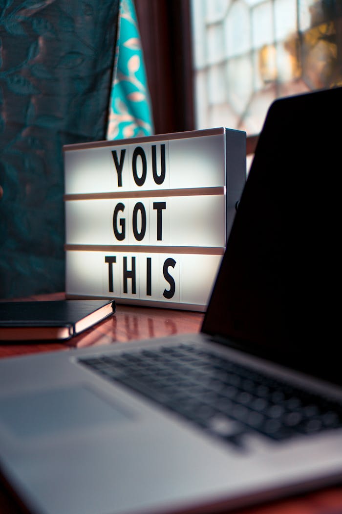 Illuminated lightbox with a motivational quote beside a laptop, promoting productivity.